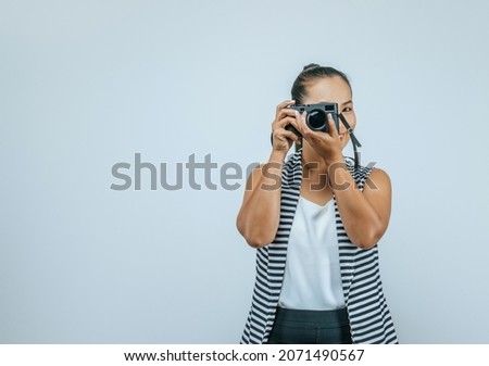 Portrait of Asian woman wearing casual clothes with a big smile on face,  taking pictures with camera. Isolated background in studio with blank space.