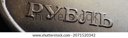 Translation: ruble. Banner or headline with the name of the Russian currency close-up. Fragment of a 1 ruble coin. Economy, finance and money of Russia. Textured scratched dirty coin. Macro