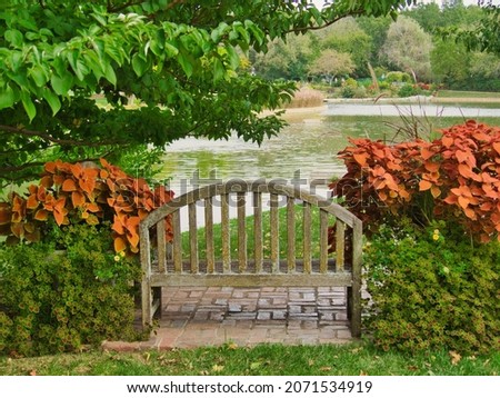 A wooden bench by the pond at Overland Park Arboretum and Botanical Gardens Royalty-Free Stock Photo #2071534919