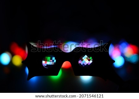 Carnival mask on the background of festive multicolored lights. Colorful bokeh, bright blurred Christmas lights and the silhouette of a carnival mask. Party time. Unfocused blurred bat mask silhouette
