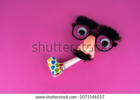 Funny face mask with big eyes, whistle and pink background with lot of copy space