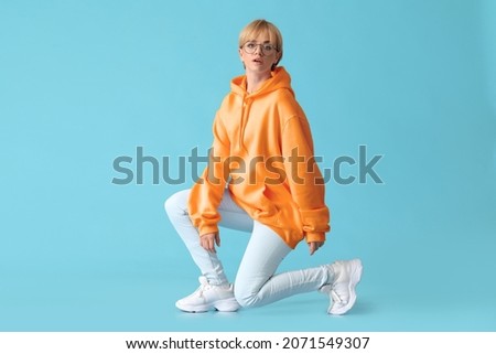Beautiful young woman in stylish hoodie on blue background