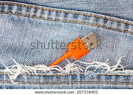 Red USB cable in jeans pocket, USB cord with the jeans pocket