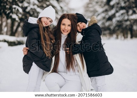 Mother with daughter and son having fun in park full of snow