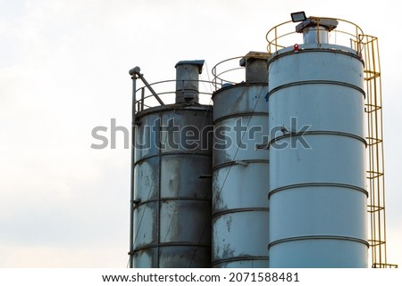 Silos of construction site. Storage towers isolated on cloudy sky background. Construction area background photo. Cement storages.