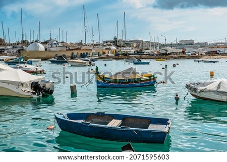 Traditional colorful Malta boats in Sliema harbor,yachts in background.Crystal clear turquoise water.Travel vacation concept.Blue-yellow fishing boat in the Mediterranean Sea.Holiday on Malta island Royalty-Free Stock Photo #2071595603