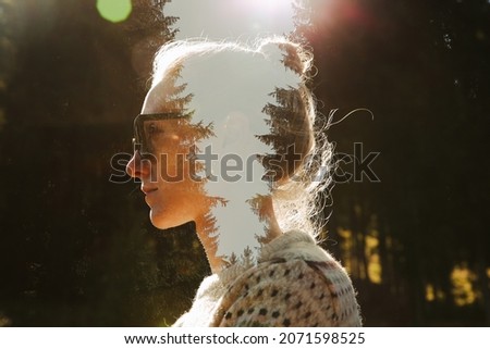 The double exposure of profile picture of young woman, wearing sunglasses, sweater, fair hair in a bun, coniferous wood, pine trees in the head, glare of the bright sun