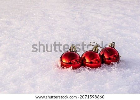 three red christmas tree balls on white snow