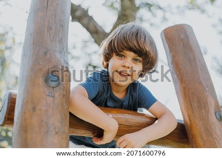 portrait of a smiling little brunette boy in a blue T-shirt playing outdoors. happy child, lifestyle. products for children. High quality photo Royalty-Free Stock Photo #2071600796