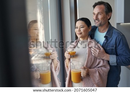 Happy couple hugging near window at home