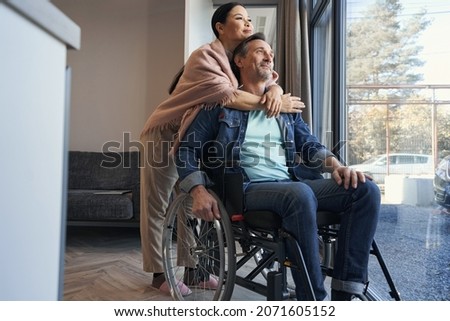 Happy man using wheelchair hugging with wife
