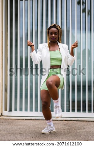 Vertical photo of a sportive african woman dancing with vitality freestyle in the street