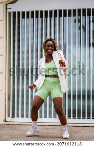 Vertical photo of a sportive african woman dancing energetically freestyle hip hop in the street
