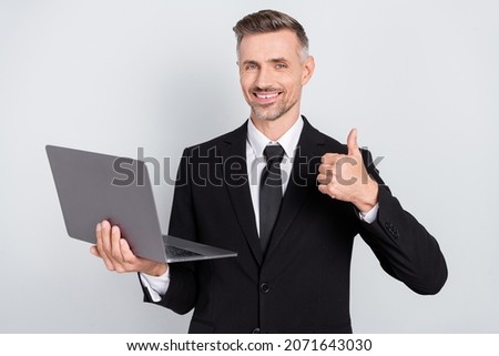 Photo of confident happy young programmer wear black jacket showing thumb up developing modern device isolated grey color background