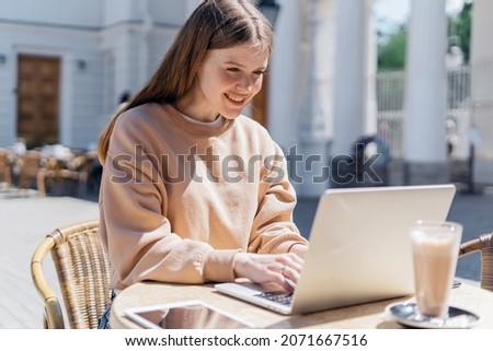 Online training. A teenager communicates with friends on a social network. The blogger writes a message to the mail. Sitting in a summer cafe on the street. A woman uses a laptop.
