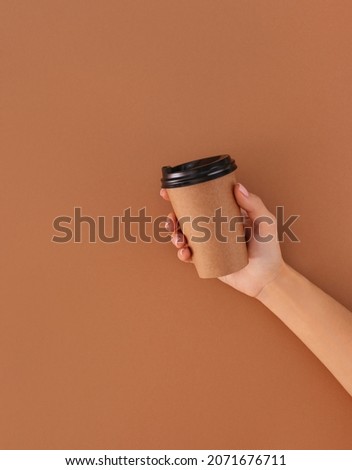 paper cup of coffee with place for logo in hand on beige background