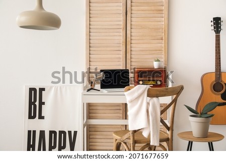 Stylish workplace with laptop and radio in room