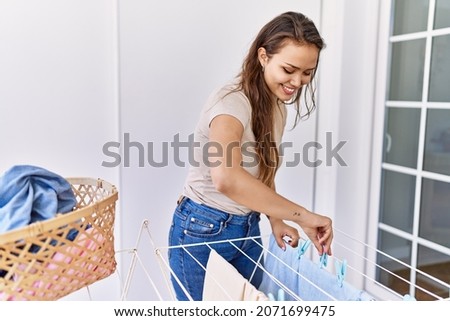 Young hispanic girl doing laundry hanging clothes at clothesline. Royalty-Free Stock Photo #2071699475