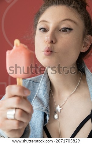 details of the face of a beautiful young woman having fun while eating ice cream, lifestyle and joy with food, wearing necklace and makeup in the daytime
