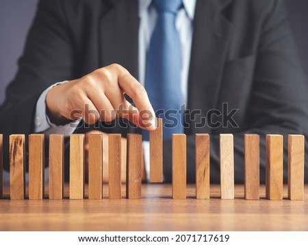 Business and risk management concept. A businessman in a suit picks up a wooden block while sitting in the office. Conceptual of planning, strategy. Close-up photo..