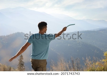 Man throwing boomerang in mountains on sunny day, back view Royalty-Free Stock Photo #2071743743