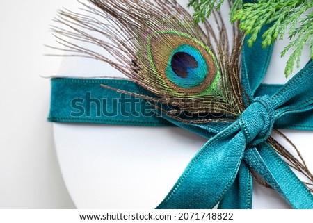 Christmas round white gift box with peacock feather composition. Winter holiday festive greeting card close up