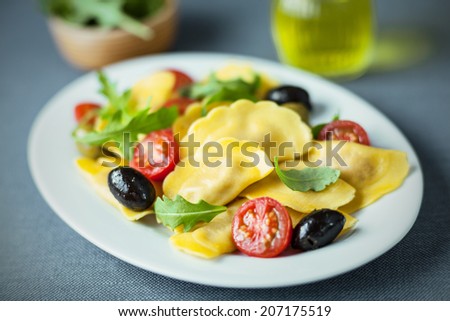 Italian ravioli salad with rocket , cured black olives and fresh cherry tomato on an oval plate, closeup with shallow dof