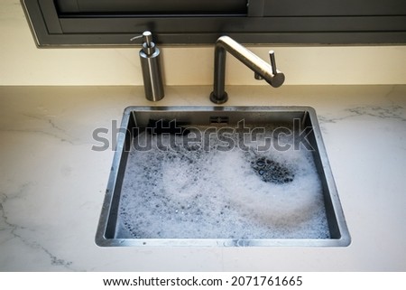 Overflowing kitchen sink, clogged drain. Plumbing problems. Foam.