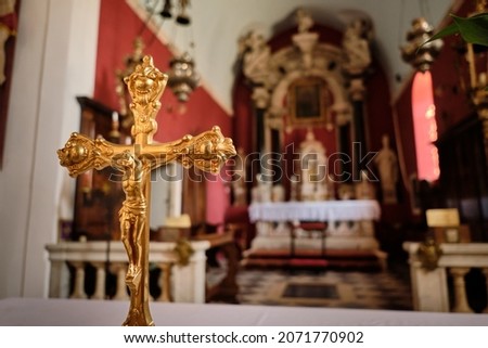 Closeup of golden crucifix in a Catholic church. On a blurred background - the interior of the cathedral.