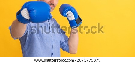 man punching in boxing gloves on yellow background, copy space, success