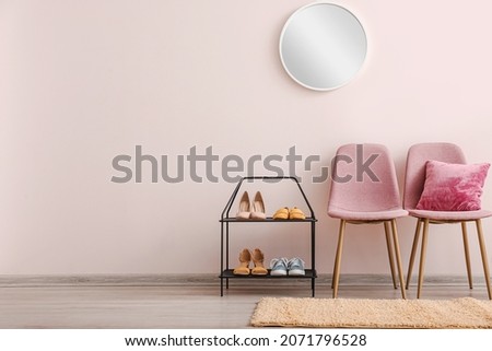 Stylish interior of hallway with shoe stand, chairs and mirror