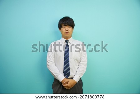 Japanese man in a suit laughing refreshingly in front of a blue background
