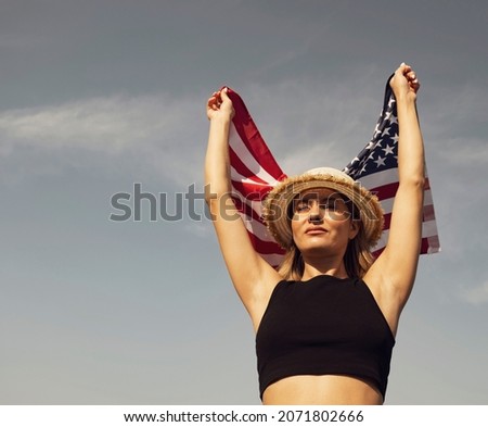 Young woman with USA flag against the sky. Brown toning