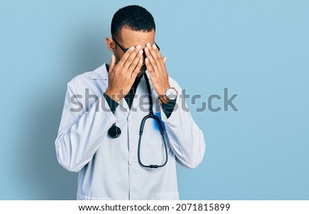 Young african american man wearing doctor uniform and stethoscope rubbing eyes for fatigue and headache, sleepy and tired expression. vision problem 