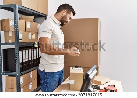 Young hispanic man smiling confident make photo to package label at storehouse