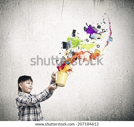 Cute boy splashing colorful paint from bucket