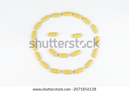 Smile emoticon mosaic of yellow pills stack on white background