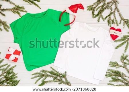 White and green t shirt mockup with copy space and Christmas Holiday template flatlay. Top view blank t-shirt on white background. Happy New Year decorations