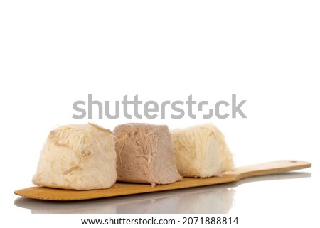 Three sweet cotton candy on a spatula made of wood, close-up, isolated on white.