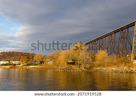 Golden hour landscape view of the Cap-Rouge River flowing into the St. Lawrence River, with a striking railway trestle bridge in the background, Cap-Rouge area, Quebec City, Quebec, Canada Royalty-Free Stock Photo #2071919528