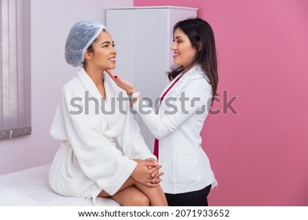 doctor or dentist evaluating the face of a beautiful afro woman for aesthetic treatment