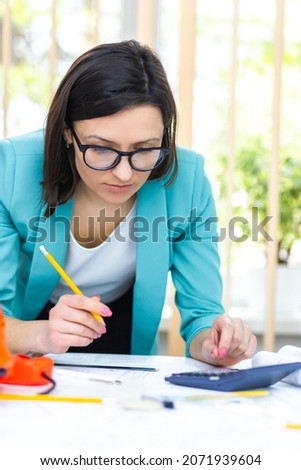 Photo of woman with pencil working with papers.