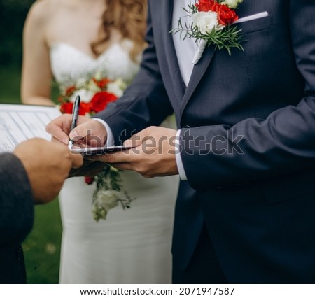 Bride and groom signing official marriage certificate on a wedding ceremony in a summer garden. Young bridal couple in love on a wedding day.
