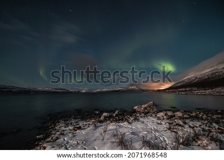 Borealis aurora sweeps over a large lake on a cloudless night in Kilpisjarvi, Lapland, Finland. aurora polaris in green dances across the sky. Scandinavian magic. Saana mountain in fog. Royalty-Free Stock Photo #2071968548