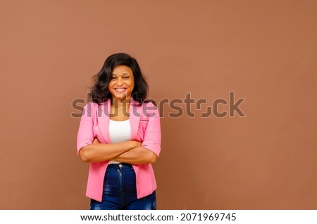 happy young african woman smiling with arms crossed and looking at camera against white studio background