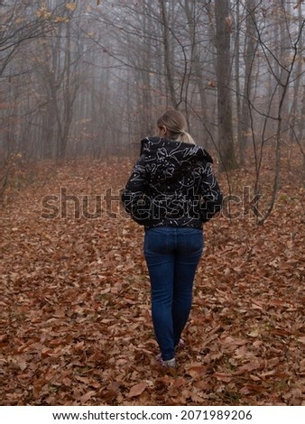 girl in a black jacket walks in the autumn forest