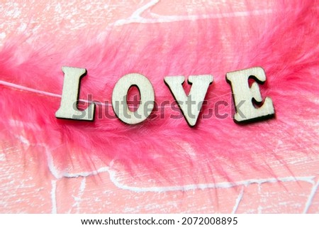 The inscription love on a pink background. Wooden letters. The inscription I love you in wooden letters on a pink background.