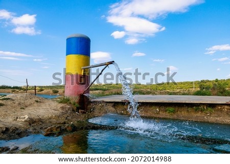 Thermal natural springs of mineral water in the village of Goteshty, Cantemir region, welcome to Moldova. The pipe is painted in the colors of the national flag. Background with copy space