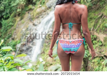 Rear View Of Young Woman Standing By Waterfall Outdoors. Vacation and Tourism Concept