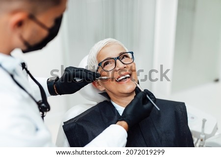 Beautiful senior woman having dental treatment at dentist's office. Dentist is wearing protective face mask due to coronavirus pandemic.	 Royalty-Free Stock Photo #2072019299